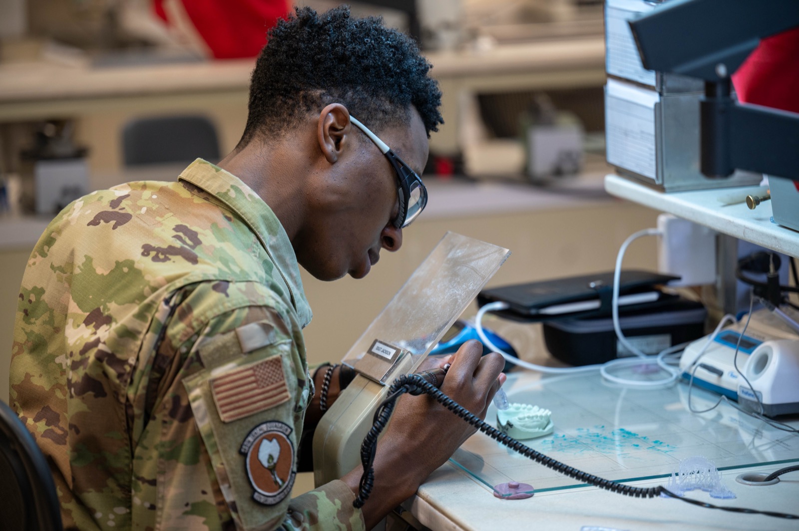 Dental laboratory technician refining a dental model at a lab bench